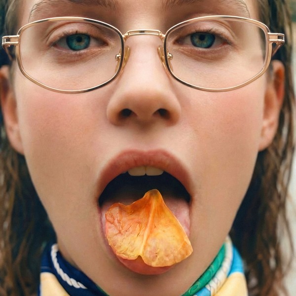 Close-up of a person wearing glasses with a flower petal resting on their tongue.