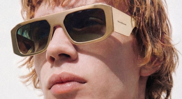 Person wearing oversized rectangular sunglasses with light-colored frames, shown at an angle against a light background.