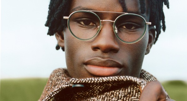 Close-up portrait of a person wearing round green-rim glasses and a scarf.