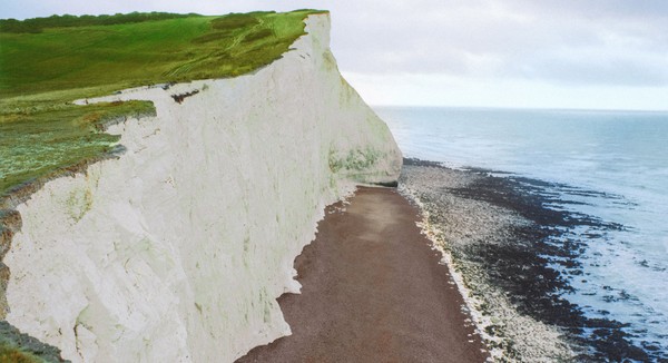 Dramatic seaside cliff view with ocean and beach below.
