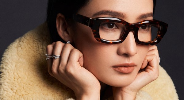 Close-up beauty shot of woman wearing tortoiseshell eyeglasses with warm-toned lenses and luxury styling