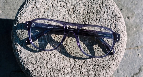 Purple bloobloom glasses displayed on a circular stone surface in sunlight.