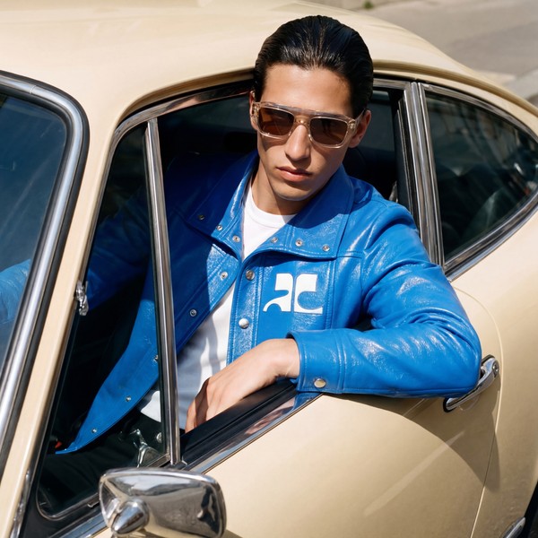 Model in sunglasses and blue jacket sitting in a vintage car