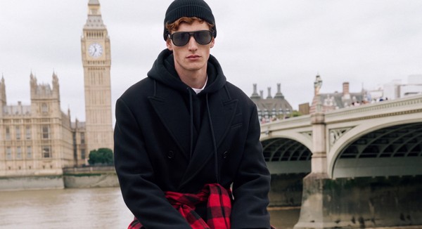 Model in black sunglasses and dark outerwear with Big Ben in the background.