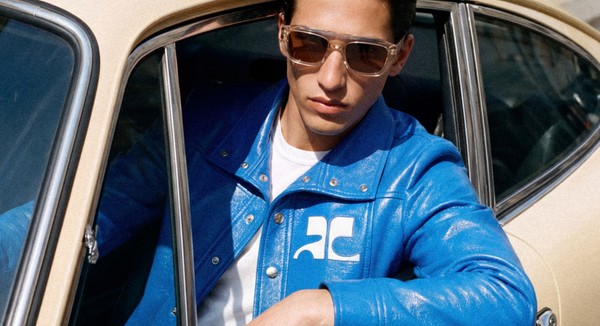 Model in sunglasses and blue jacket sitting in a vintage car