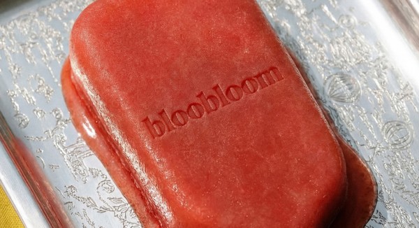 Red bloobloom ice lolly melting on a silver tray